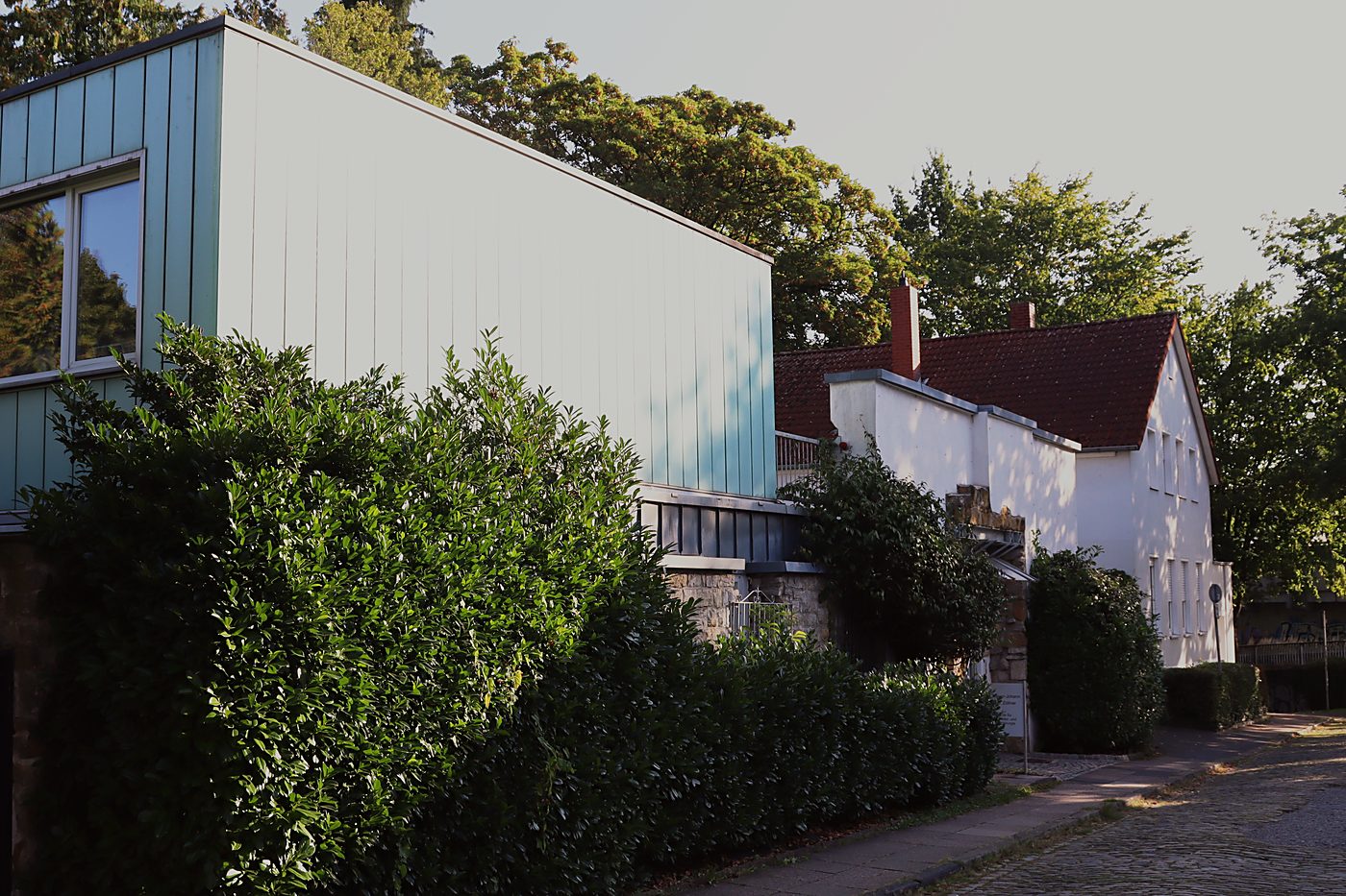 Gepflasterter Weg entlang der Hecke zum Praxisgebäude